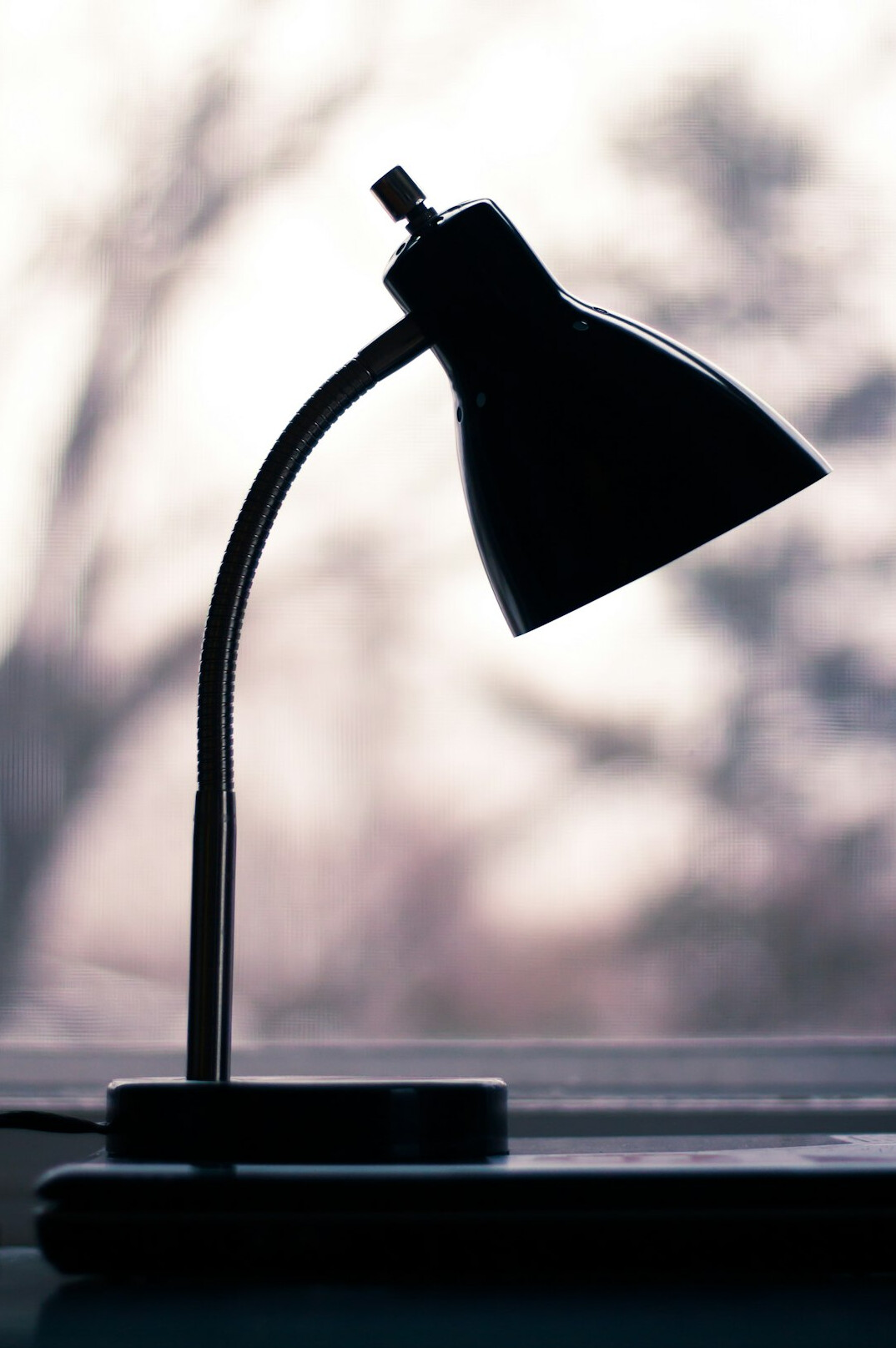 Old typewriter on a wooden desk lit by a warm lamp beside a foggy window